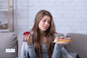 Young woman looking conflicted while holding desserts, symbolizing eating disorder treatment and recovery at Empower Health Group