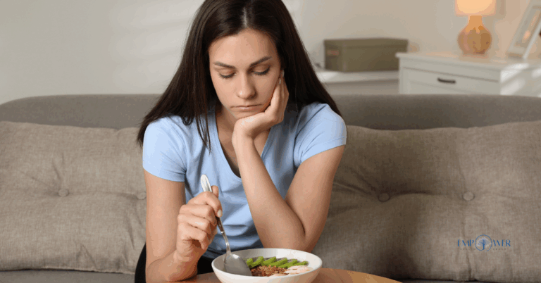 Young woman sitting on couch looking at bowl of food, symbolizing avoidant restrictive food intake disorder treatment at Empower Health Group