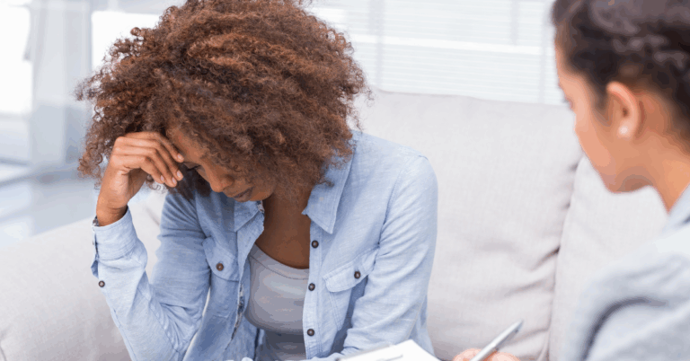 Woman looking distressed while speaking with another person during a counseling or support session.