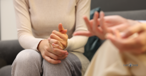 Close-up of a patient's hands clasped together during a session to show the emotional support and benefits of CBT in addiction recovery.
